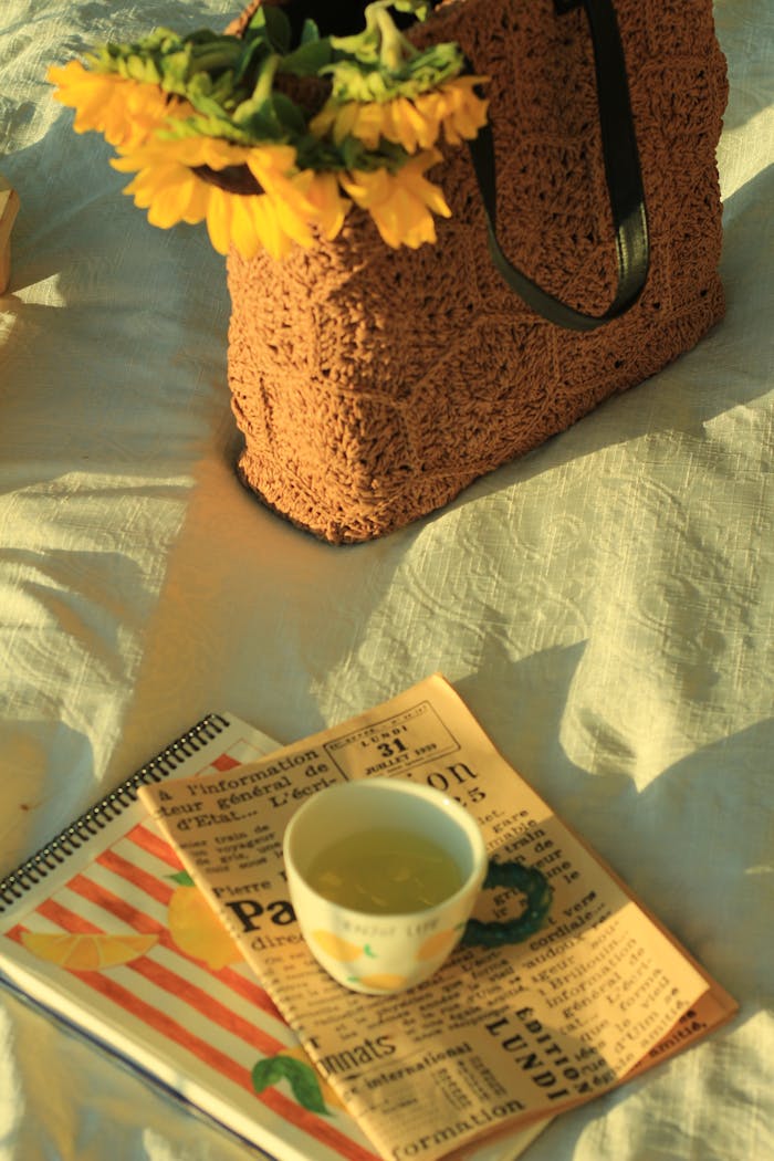 services-03 A cozy scene featuring a woven bag with sunflowers, tea, and notebooks bathed in warm sunlight.